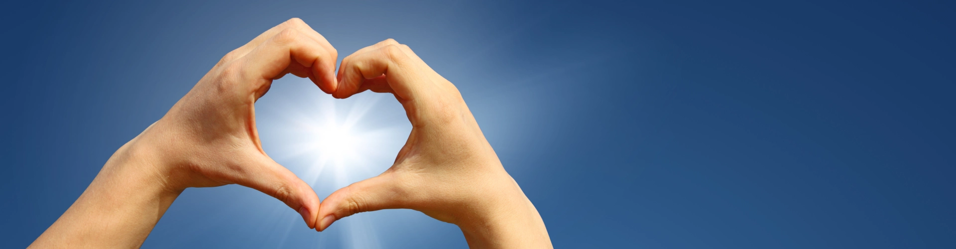 Hands frame the sun in a heart shape, representing hope and brighter futures together.