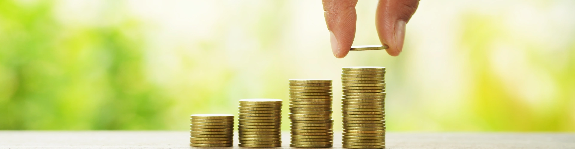 Hand places coins on growing stacks to support charitable giving and community investment.